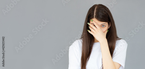 Young woman with hand on her face isolated on gray background, facepalm