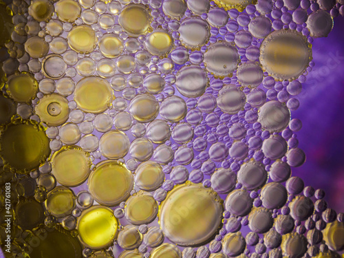 Colorful macro shot of olive oil bubbles in a colored glass of water