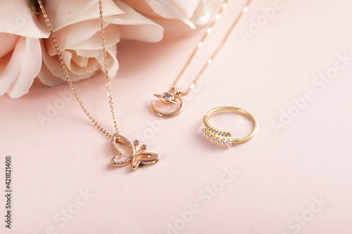 High angle shot of a beautiful ring and necklaces on a pink surface