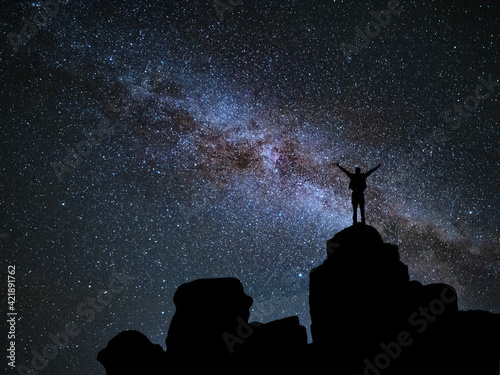 Man standing at mountain and looks in night sky