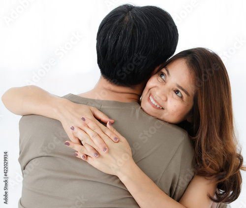 Horizontal back view portrait of senior Asian husband hugging his wife. A lovely couple standing closely and embracing each other with a warm hug. Concept of a romantic relationship in elderly