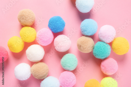 Closeup shot of colorful soft pom pom balls on pink background