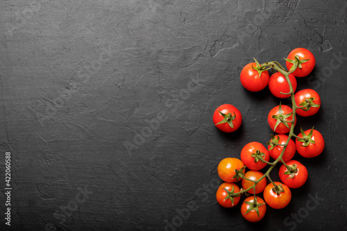 Cherry tomatoes on a black background, top view.