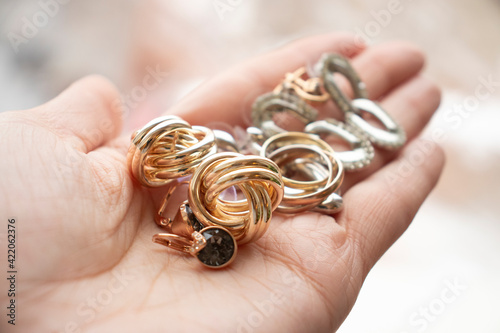 jewelry made of red and white gold: rings, earrings lie in a woman's palm. Women's things, treasures. Street trade, choice, style, fashion accessories