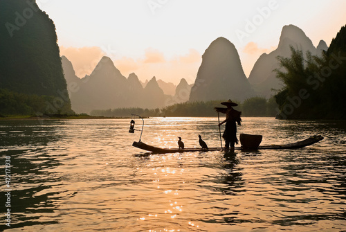 Silhouette of cormorant fisherman on the Li River (Lijiang) with karst peaks in the background at sunset, near Xingping, Guangxi Province, China