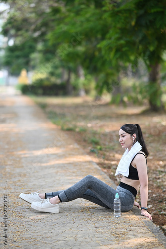 Portrait of healthy female taking a break and sitting outdoors after workout.