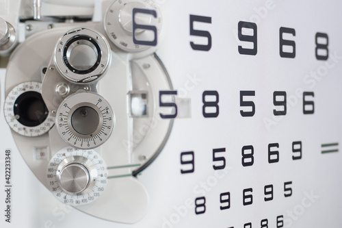 Close up of phoropter eyesight measurement testing machine with double exposure test chart vision optician check up number, Eye health check and ophthalmology concept.