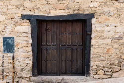 Old wooden door in stone wall in traditional house in the village of Horcajuelo de la Sierra in Madrid