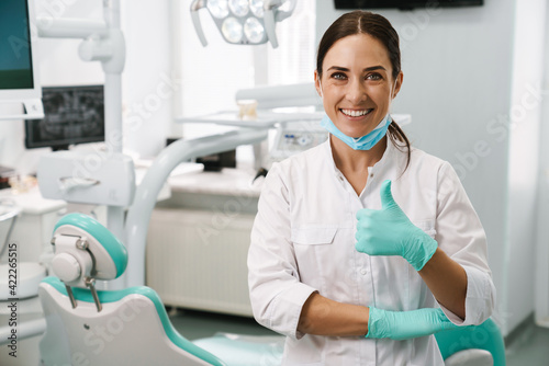 European mid dentist woman showing thumb up in dental clinic