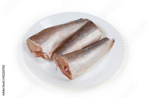 Defrosted uncooked Argentine hake carcasses on a white dish