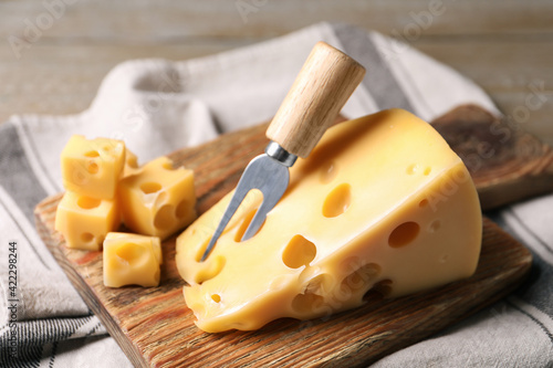 Tasty fresh cheese with fork on wooden board, closeup