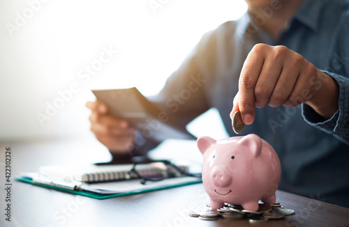 Close-up image of man hand putting coins in pink piggy bank for account save money. Planning step up, saving money for future plan, retirement fund. Business investment-finance accounting concept.