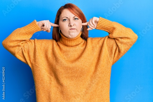 Beautiful redhead woman putting fingers on ears ignoring noise skeptic and nervous, frowning upset because of problem. negative person.