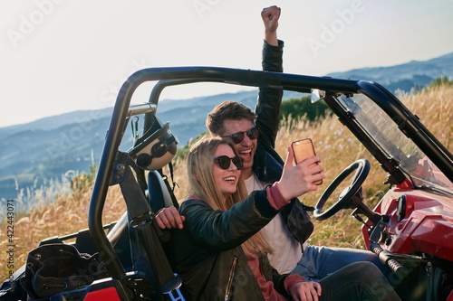 couple enjoying beautiful sunny day taking selfie picture while driving a off road buggy