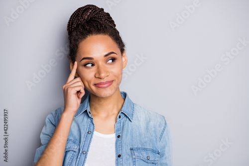 Photo portrait of african american woman touching temple with finger looking at blank space isolated on clear grey colored background