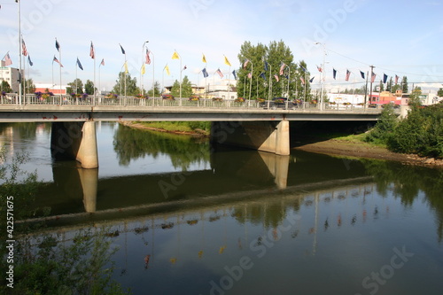 Centennial Bridge, Fairbanks with Flags and a Reflection in the Chena River, Fairbanks, Alaska next to Golden Heart Plaza and the Inuit Statue