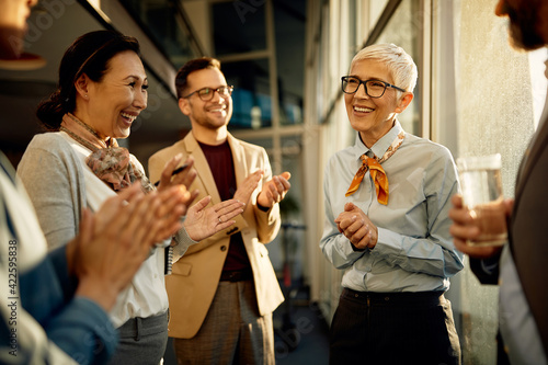 Group of happy business people applauding to their female executive manager in the office.