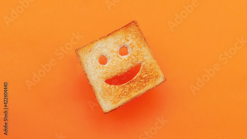 Funny smiling bread toast on a orange background. Good mood, positive emotions, joy, happiness, good morning, delicious breakfast for kids
