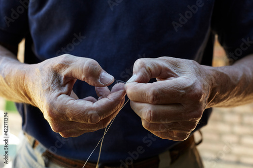 Senior man tying a fly for fishing