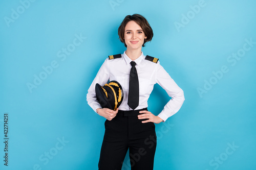 Photo of happy pretty young woman hold hand waist good mood pilot isolated on pastel blue color background