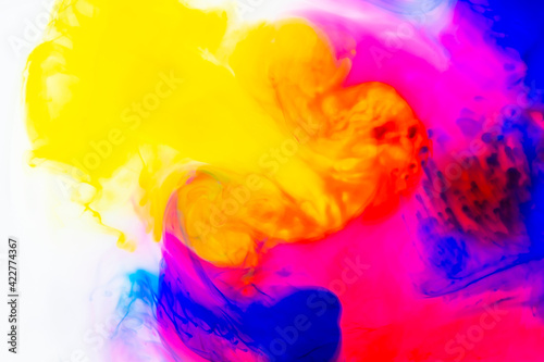 Photo of rainbow streams of paint in water. Dynamic drawing of ink flow. Curls and swirls of liquids. Abstract bright pattern.