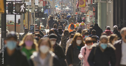 Anonymous crowd of people walking street wearing masks during Covid 19 pandemic in New York City