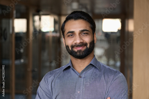 Portrait of young happy indian business man executive looking at camera. Eastern male professional teacher, smiling ethnic bearded entrepreneur or manager posing in office, close up face headshot.