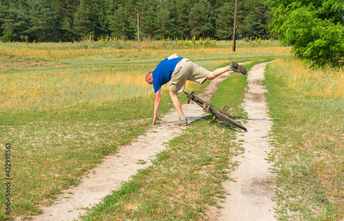 Mature man falling off of an ancient bicycle on a country road in rural village Mala Rublivka in central Ukraine