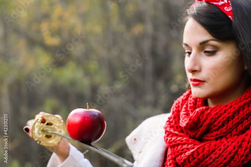 An apple on the edge of a sword in the hands of a young woman. Japanese sword.