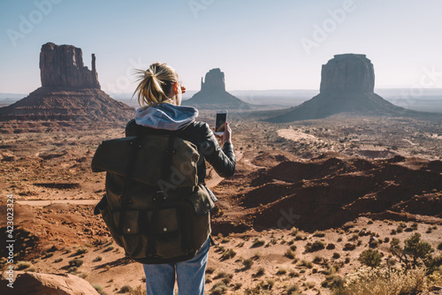 Unrecognizable female traveler taking photo of Monument Valley