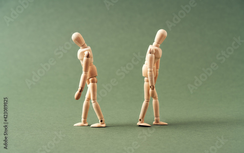 Two wooden figures walking away from each other on green background