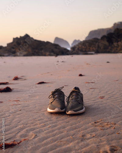 buty pozostawione na dzikiej plaży o zachodzie słońca