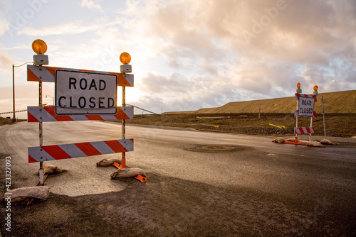 Closed road signs on an empty and deserted road with bleak sky