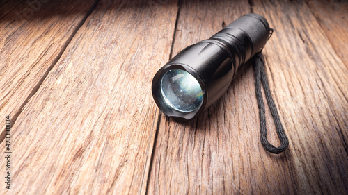 black metal flashlight on wooden floor