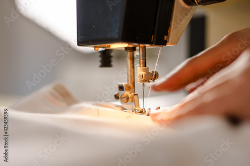 Close up on hands of unknown woman sewing on electric sewing machine