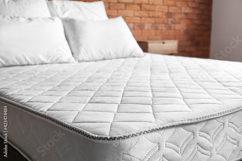 Bed with comfortable orthopedic mattress in room