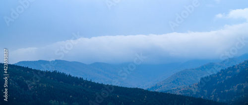 Panorama of mountains and cloudy sky during rain 