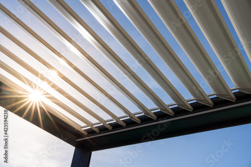 Trendy outdoor patio pergola. the sun's rays pass through the metallic structure