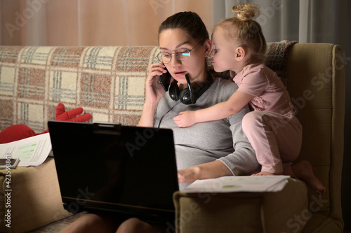 Young pregnant woman tries to work remotely, but her little daughter interferes