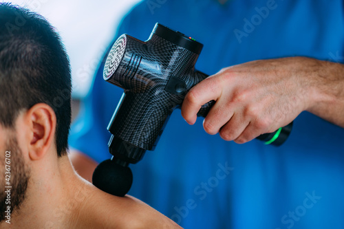Therapist Treating Patient’s Trapezius Muscle with Massage Gun