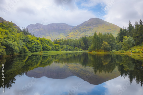 Idyllic, lush and green mountain landscape reflection on a calm Torren Lochan on a summer day at Glencoe in the Scottish Highlands, Scotland.