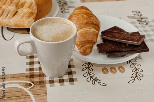 Kawa na stoliku, maślany rogalik i czekolada na talerzyku