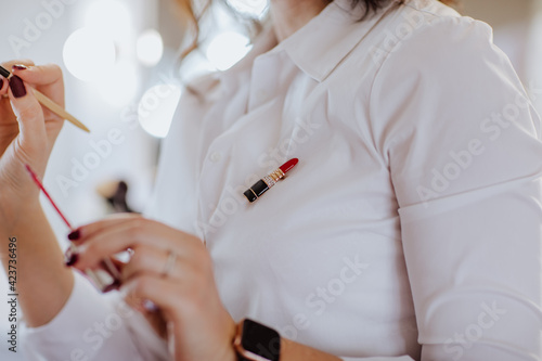 Cute brooch like a lipstick on white shirt. Make up business concept.