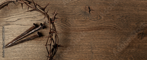 Crown of thorns with three nails on wooden background. Easter concept.