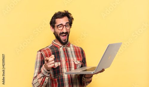 young crazy bearded man pointing or showing and a laptop