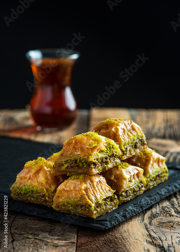 BAKLAVA. Traditional Turkish Desserts Baklava with Turkish Tea. Crispy pistachio baklava on black plate.