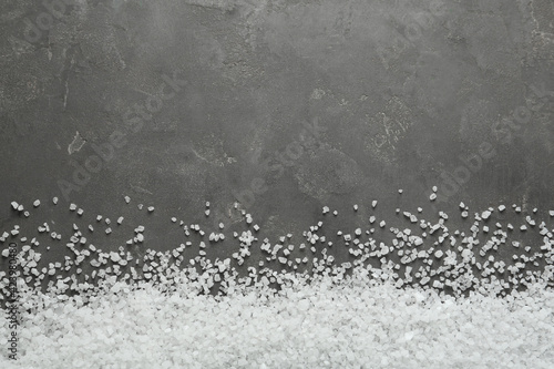 Natural sea salt on grey table, flat lay. Space for text