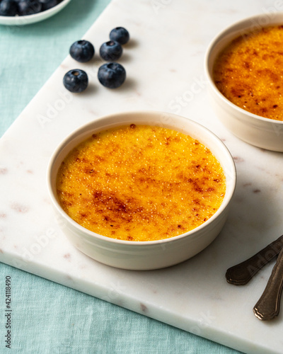 Ramekin with Spanish crema catalana. Traditional French vanilla Creme brulee dessert. Burned cream, burnt or Trinity creme. Rich custard base topped hardened caramelized sugar. Side view, vertical