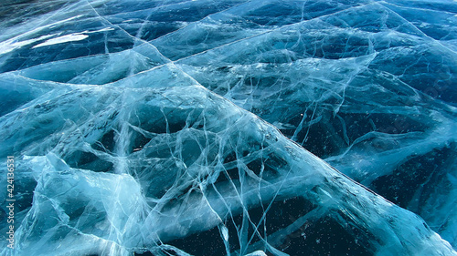 Unique pattern of frozen Lake Baikal. Blue transparent clear smooth ice with deep cracks.