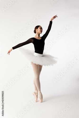 Young ballerina dancing on white background